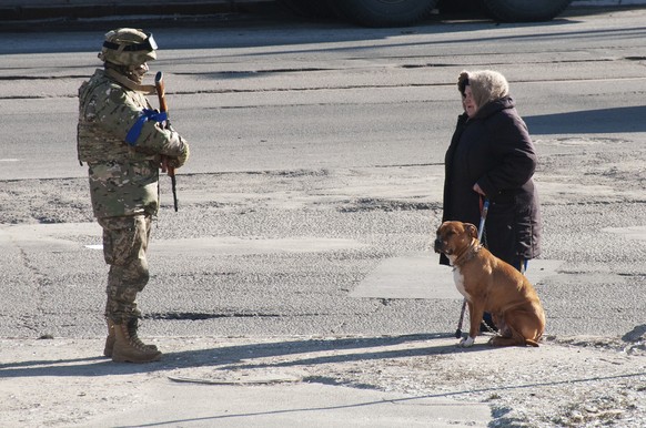 A Ukrainian serviceman talks with a woman walking her dog in a street near the site of the National Academy of State Administration building damaged by shelling in Kharkiv, Ukraine, Friday, March 18,  ...