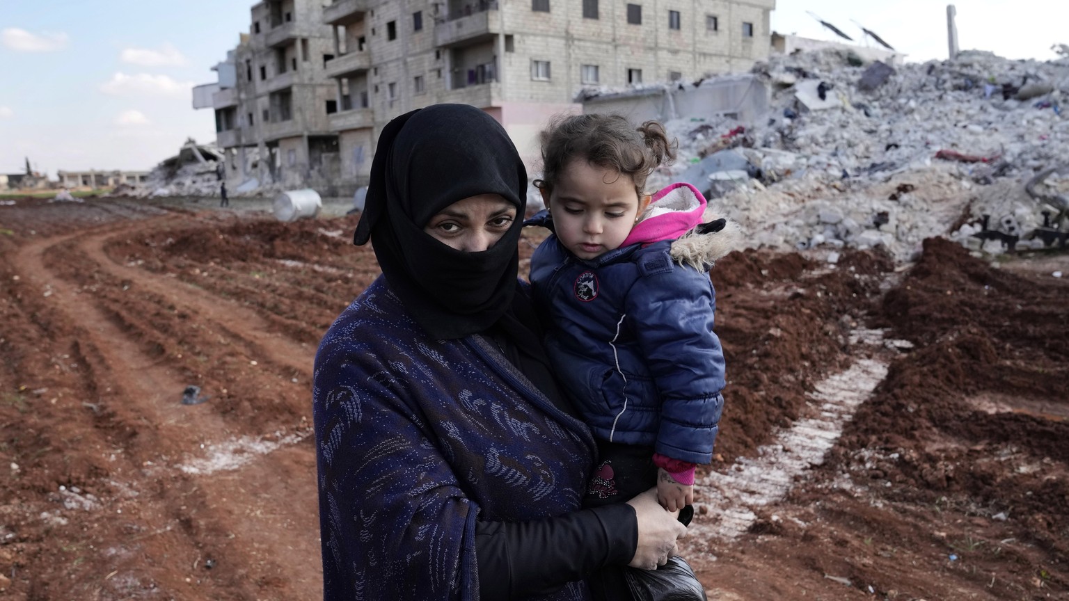 Ayesha, who lost her home in the devastating earthquake, carries her granddaughter in Atareb, Syria, Sunday, Feb. 12, 2023. After the earthquake, the 43-year-old has had no access to water, electricit ...