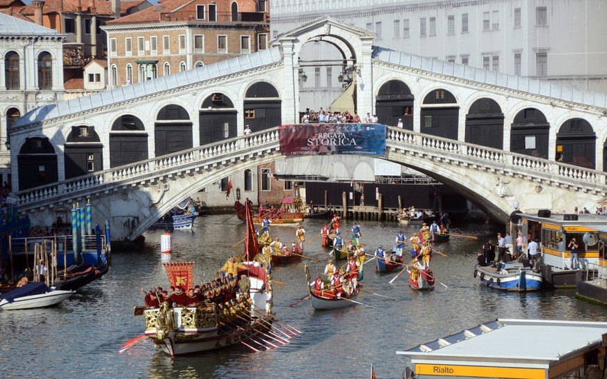 The Bucintoro, the barge of Venice&#039;s ruler, the Doge, leads a parade of historical Venetian boats as it sails past the Rialto bridge along the Grand Canal during the Historical Regatta in Venice, ...