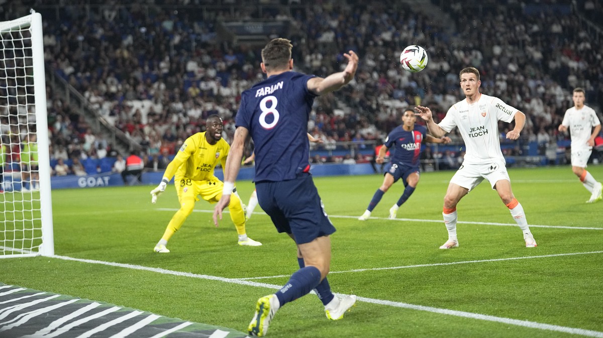 Lorient's goalkeeper Yvon-Lamdry Mvogo, watches as PSG's Fabian Ruiz, centre and Lorient's Julien Laporte challenge during the French League One soccer match between Paris Saint-Germain ...