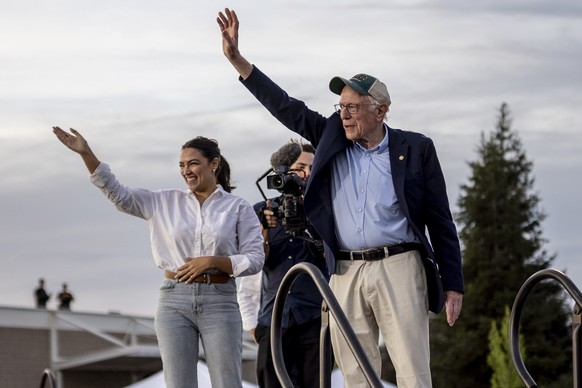 Rep. Alexandria Ocasio-Cortez (D-NY), left, and Sen. Bernie Sanders (I-VT) wave during a stop of the &#039;Fighting Oligarchy&#039; rally at Folsom Lake College in Folsom, Calif., Tuesday, April 15, 2 ...