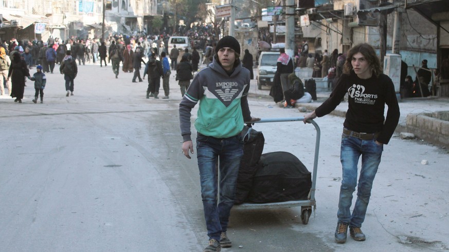 epa05677967 Two Syrians pull their baggage during the evacuation, Aleppo, Syria, 15 December 2016 (issued 16 December 2016). Evacuation of civilians from the rebel-held parts of Aleppo was suspended a ...