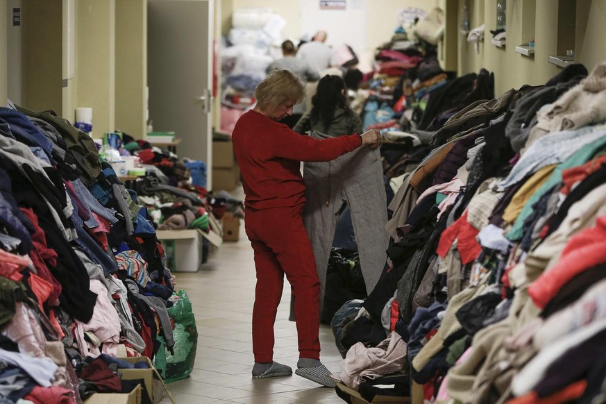 A woman searches trough donated clothes inside a sports hall to accommodate Ukrainian refugees fleeing Russian invasion at the border crossing town of Medyka in Poland, on Tuesday, March 1, 2022. All  ...