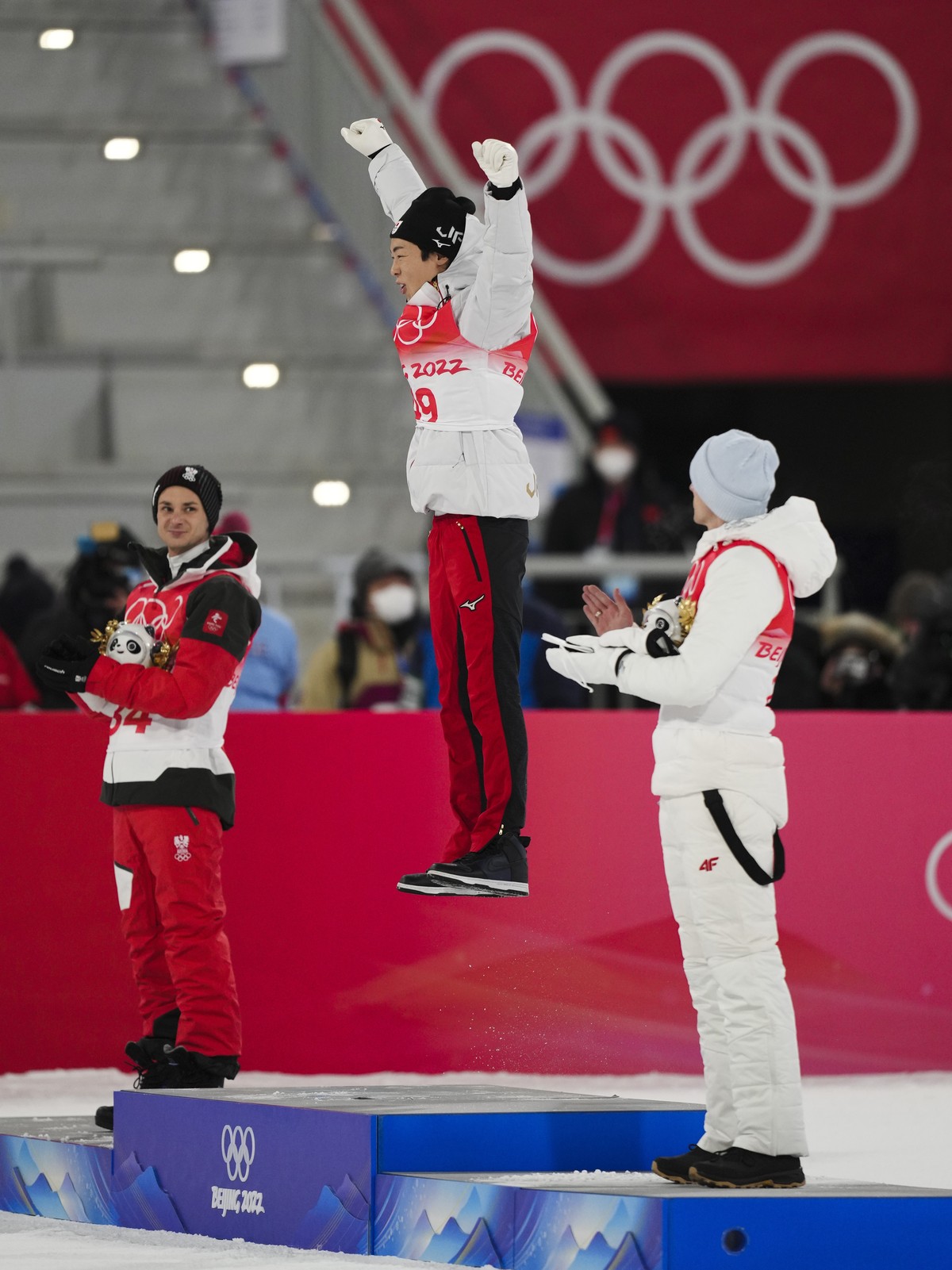 Ryoyu Kobayashi, of Japan, center, celebrates celebrates after winning gold as Manuel Fettner, of Austria, left, and Constantin Schmid, of Germany, watch during the flower ceremony for the men's  ...
