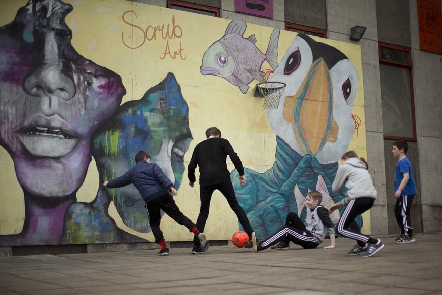 A youth worker and children at a youth center play soccer in front of a mural which includes a Puffin bird, a species which breed in large numbers on the Faeroe Islands and are part of the local cuisi ...