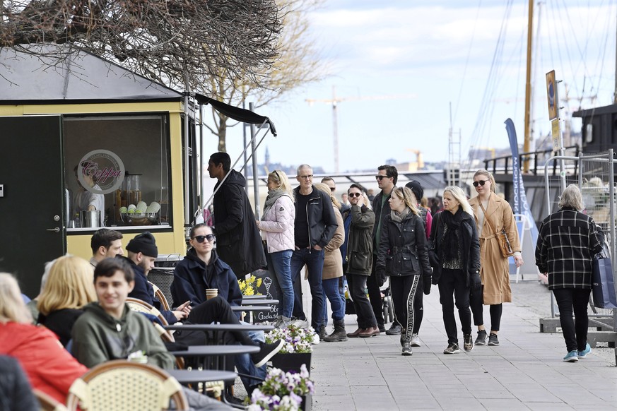 epa08371645 People queue to buy ice cream while enjoying the beautiful spring weather amid the ongoing coronavirus COVID-19 pandemic at Norr Malarstrand street in central Stockholm, Sweden, 19 April 2 ...