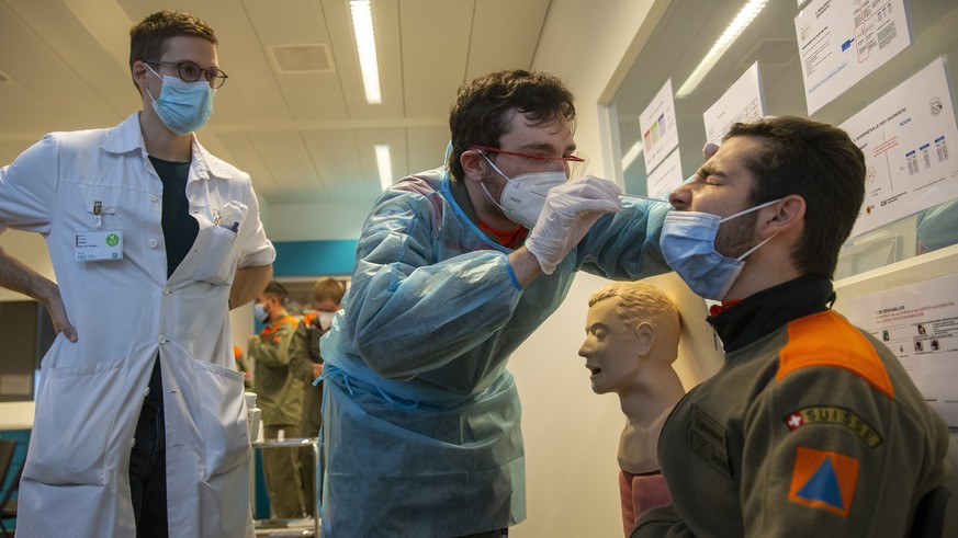 epa08810353 A member of the Swiss Civil Protection, under glance of doctor Francois Voruz, takes a nose swab sample from a model for a polymerase chain reaction (PCR) for a SARS-CoV-2 Rapid Antigen Te ...