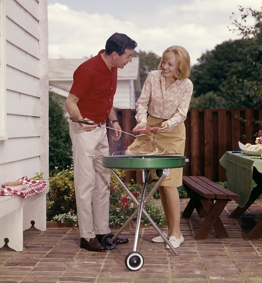 1960s COUPLE MAN WOMAN GRILLING STEAK ON BACKYARD PATIO BAR-B-CUE CHARCOAL GRILL (Photo by H. Armstrong Roberts/ClassicStock/Getty Images)