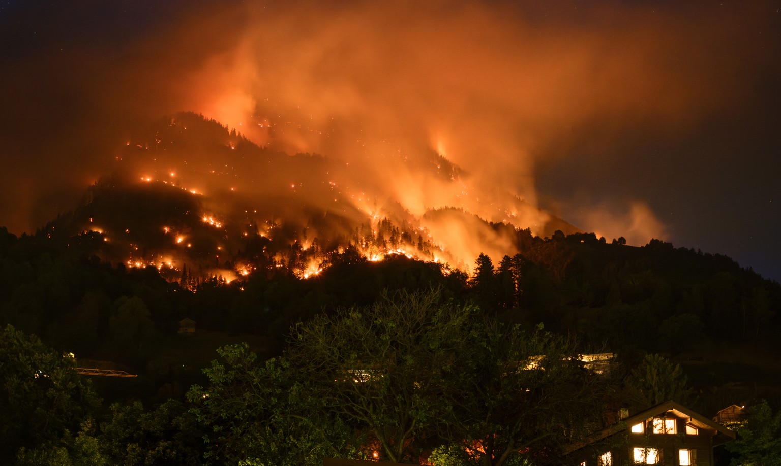 epa10753038 Smoke and flames rise from the burning forest above the communes of Bitsch and Ried-Moerel, in Bitsch, Switzerland, 17 July 2023 (issued 18 July 2023). A forest fire broke out above Bitsch ...