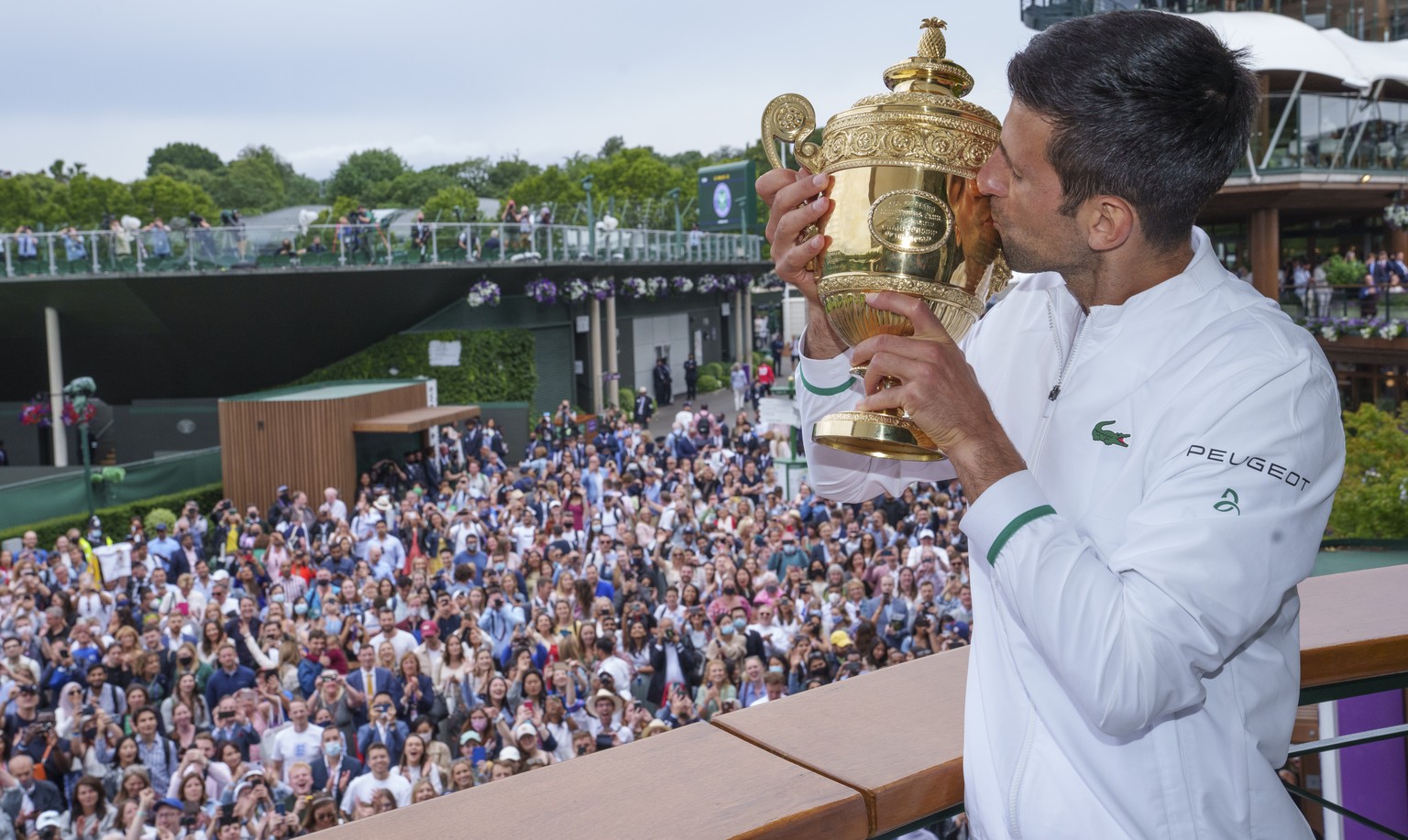 epa09338205 Spectators watching on as Novak Djokovic of Serbia poses with the Gentlemen&#039;s Singles Trophy on the balcony of the Clubhouse after winning the Gentlemen&#039;s Singles at The Wimbledo ...