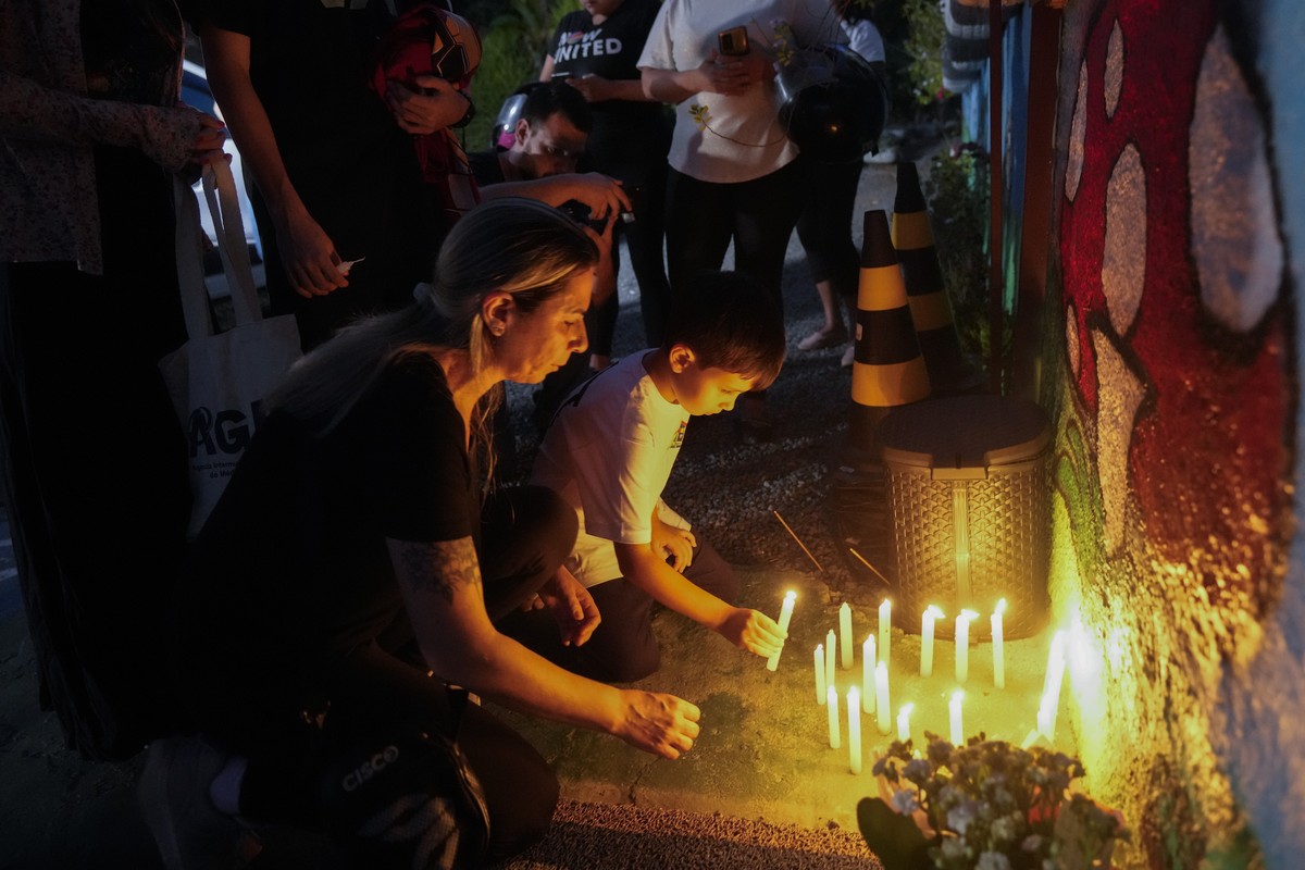 People place lit candles outside the "Cantinho do Bom Pastor" daycare center after a fatal attack on children in Blumenau, Brazil, Wednesday, April 5, 2023. A man with a hatchet jumped over  ...