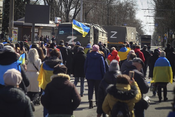 People with Ukrainian flags walk towards Russian army trucks during a rally against the Russian occupation in Kherson, Ukraine, Sunday, March 20, 2022. Ever since Russian forces took the southern Ukra ...