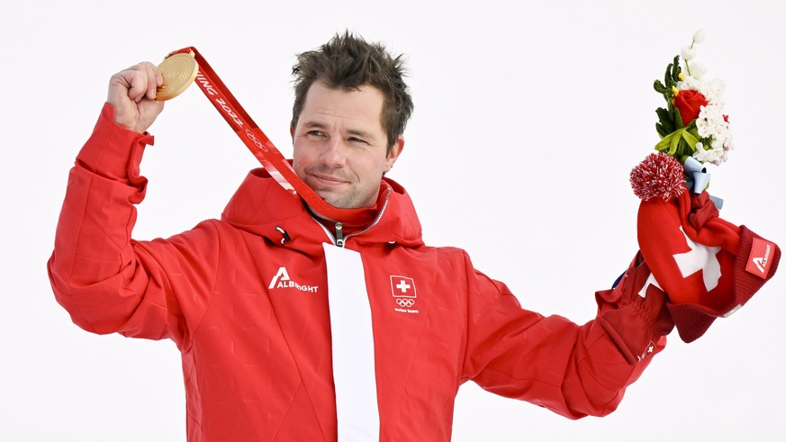 epa09734840 Gold medalist Beat Feuz of Switzerland celebrates during the medal ceremony for the Men&#039;s Downhill race of the Alpine Skiing events of the Beijing 2022 Olympic Games at the Yanqing Na ...