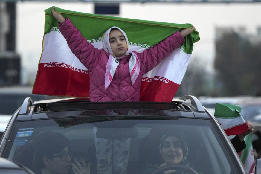 An Iranian girl holds up her country's flag during a street celebration after Iran's national soccer team defeated Wales in Qatar's World Cup, at Sadeghieh Sq. in Tehran, Iran, Friday, Nov. 25, 2022. ...