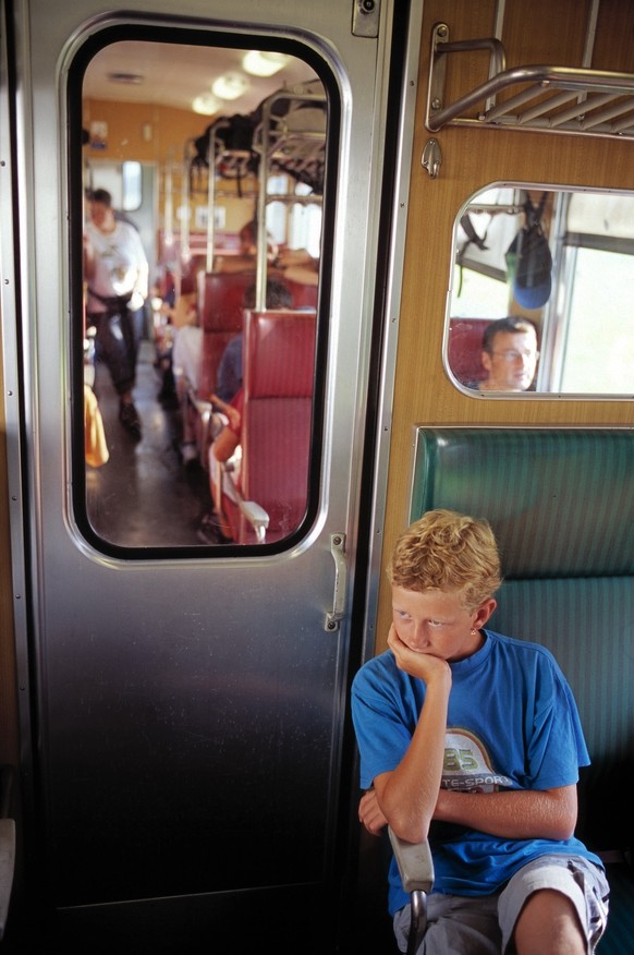 Ein Junge sitzt im Zug beim Durchgang in das Raucherabteil, aufgenommen auf der Fahrt von Arth-Goldau nach Airolo am 26. August 2003. (KEYSTONE/Martin Ruetschi) === , === : DIA]