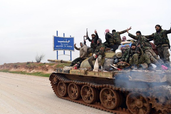 In this photo released Wednesday, Feb. 12, 2020, by the Syrian official news agency SANA, Syrian government soldiers on a tank hold up their rifles and flash victory signs, as they patrol the highway  ...