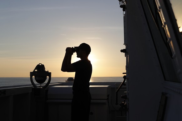 In this Feb. 22, 2017 photo, a U.S. Coast Guard sailor scans the horizon with his binoculars just outside the bridge of the USCG cutter Stratton as it navigates the eastern Pacific Ocean near the coas ...