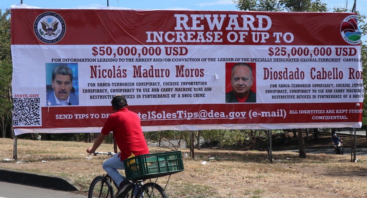 epaselect epa12318963 A man looks at a billboard with images of Venezuelan President Nicolas Maduro and Venezuelan Minister of Interior Relations, Justice, and Peace Diosdado Cabello in Villa del Rosa ...