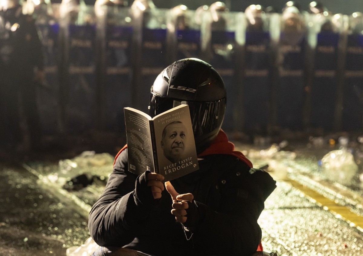 epa11983939 A protester reads Erdogan's book in front of Turkish riot police barricades as demonstrators attempt to march to Taksim Square from the Istanbul Municipality headquarters during a pro ...