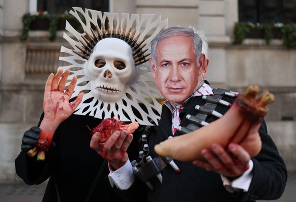 epa10994749 Demonstrators in satirical costumes depicting death and Israeli Prime Minister Benjamin Netanyahu pose with fake body parts at a pro-Palestinian march in London, Britain, 25 November 2023. ...