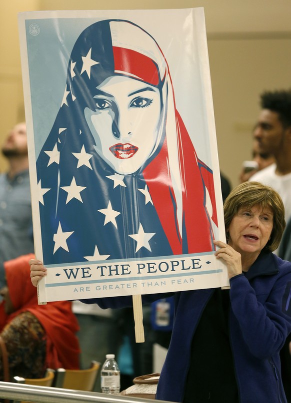 Cheryl Pollman holds a sign during a protest against President Donald Trump&#039;s executive order banning people coming from certain Muslim-majority countries from entering the U.S. at Terminal D at  ...