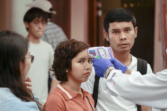 epa08224919 A visitor has her temperature checked before entering the uddha Tooth Relic Temple in the Chinatown district of Singapore, 17 February 2020 (issued 18 February 2020). The Singapore governm ...