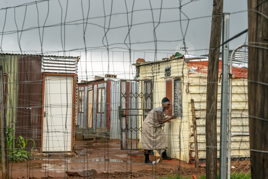 A woman living in the Vlakfontein informal settlement outside Johannesburg, South Africa, shuts her window during a rainstorm, Monday Dec. 13, 2021. South Africa's 7-day rolling average of daily new C ...