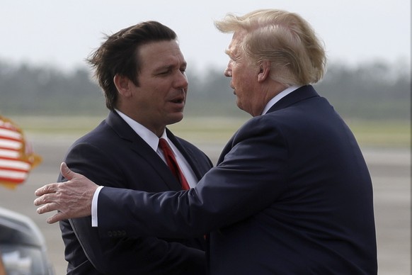 FILE - President Donald Trump shakes Florida Governor's hand.  Ron DeSantis as he arrives at Tyndall Air Force Base to review Hurricane Michael damage and attend a political rally, May 8, 2019, on T...
