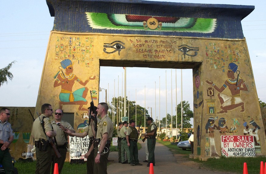 Unidentified Putnum County Sheriffs deputies stand guard at the entrance to United Nuwaubian Nation of Moors village during a raid in Eatonton, Ga., Wednesday, May 8, 2002. Authorities on Wednesday ar ...