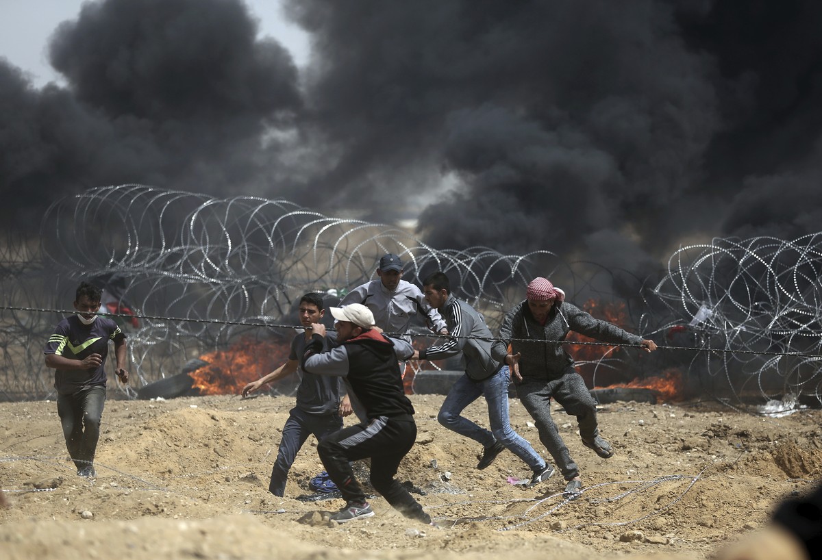 Palestinian protesters pull part of the fence that the Israeli Army placed, during a protest at the Gaza Strip's border with Israel, Friday, April 13, 2018. (AP Photo/ Khalil Hamra)