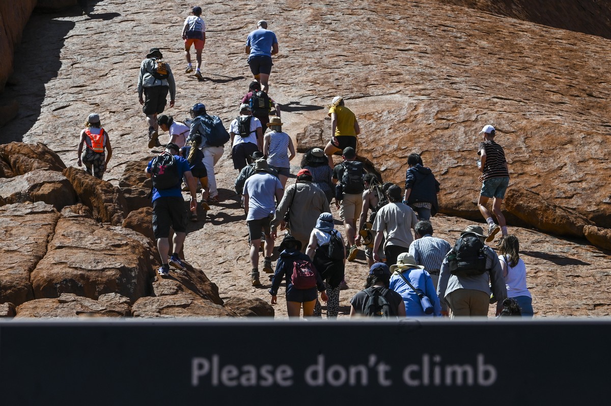 epa07948051 Tourists climb Uluru, Australia's iconic sandstone formation, in Uluru-Kata Tjuta National Park in Northern Territory, Australia, 25 October 2019. Tourists have been flocking to Uluru ...