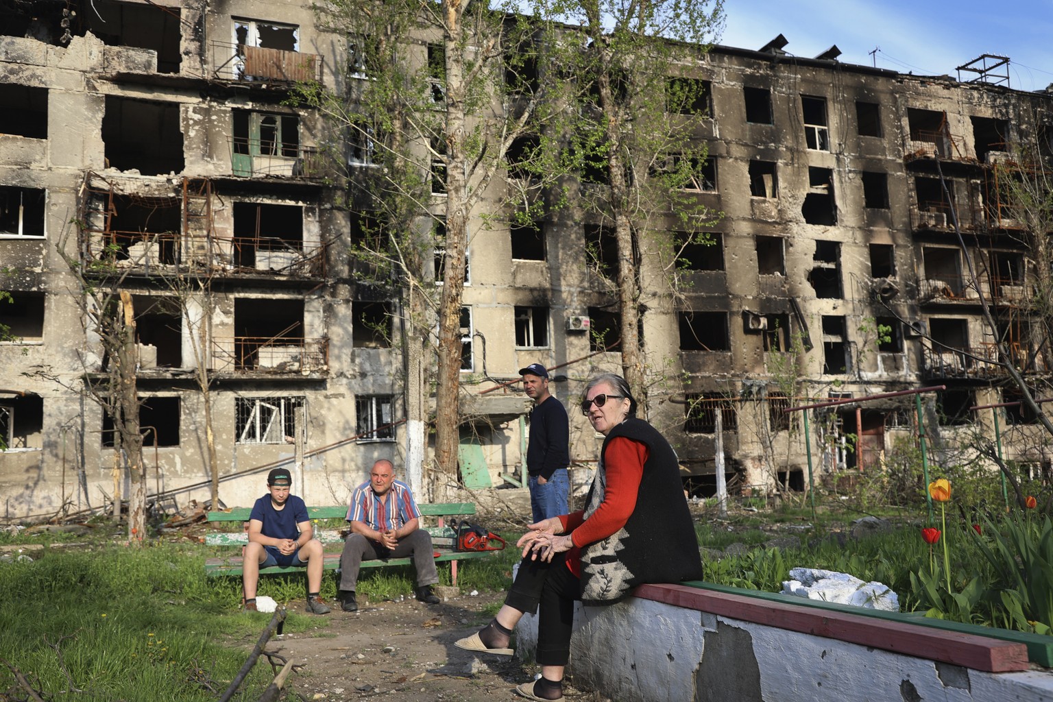 Local residents sit in the yard of their damaged building in Mariupol, in territory under the government of the Donetsk People&#039;s Republic, eastern Ukraine, Friday, April 29, 2022. (AP Photo/Alexe ...