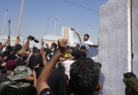 Supporters of Shiite cleric Muqtada al-Sadr try to remove concrete barriers in the Green Zone area of Baghdad, Iraq, Monday, Aug. 29, 2022. (AP Photo/Hadi Mizban)