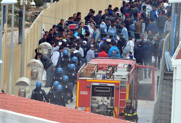 epa02682648 Police intervene to restore order at the migrant reception centre holding around 1,000 Tunisians on Lampedusa, southern Italy on 11 April 2011. Part of the centre was in flames following a ...