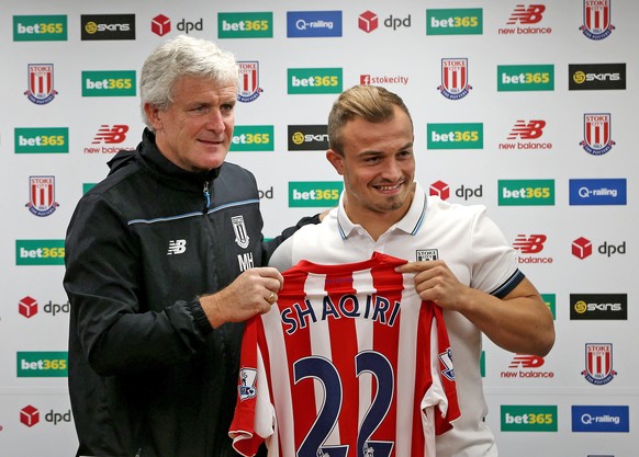 Stoke City&#039;s new signing Xherdan Shaqiri, right, holds up a tean shirt as he attends a press conference with manager Mark Hughes at the Britannia Stadium, Stoke-on-Trent England Thursday Aug. 13, ...