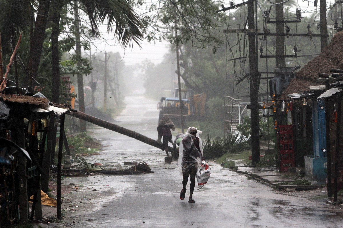 epa08433356 A man walks in heavy rain and wind as cyclone Amphan approaches the Odisha coast, Paradeep, India, 20 May 2020. Cyclone Amphan, termed as 'super cyclone' approaches through the B ...