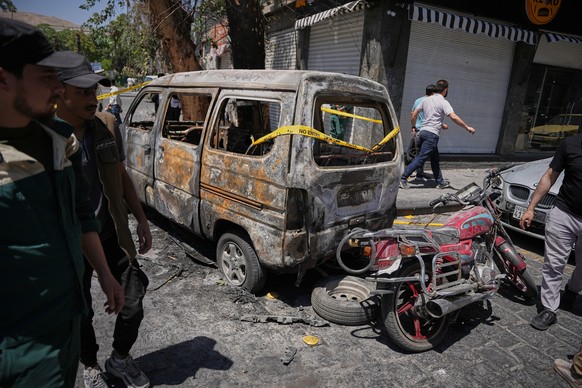 Syrian security personnel inspect a burned vehicles near the Four Seasons Hotel after two explosions rocked the area earlier while Syrian President Ahmad al-Sharaa was meeting French President Emmanue ...