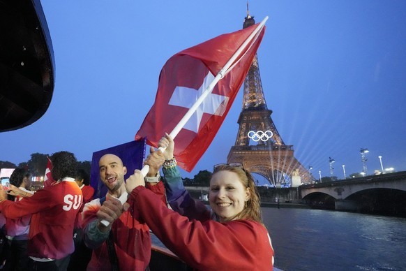 Switzerland&#039;s Nina Christen and Nino Schurter wave their country&#039;s flag in Paris, France, during the opening ceremony of the 2024 Summer Olympics, Friday, July 26, 2024. (Martin Meissner/Poo ...