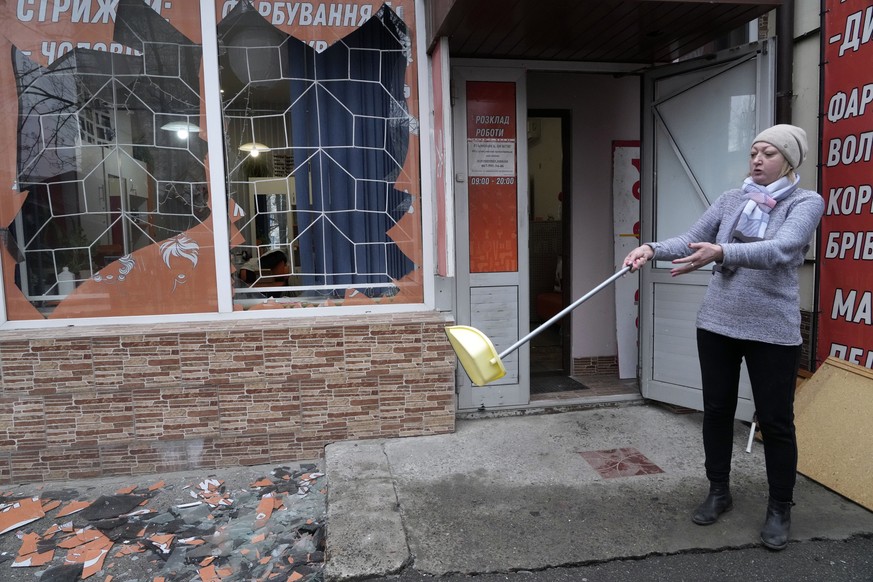 A woman sweeps up the aftermath after Russian shelling in Kyiv, Ukraine, Thursday, Feb. 24, 2022. Russian troops have launched their anticipated attack on Ukraine. Big explosions were heard before daw ...
