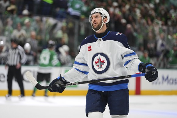 Winnipeg Jets defenseman Colin Miller skates on the ice as Dallas Stars' Wyatt Johnston, rear at bench, celebrates his goal in the third period of Game 3 of a second-round NHL hockey playoff seri ...