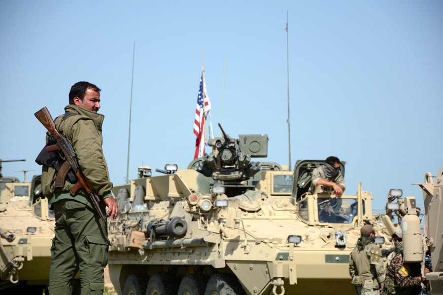 epa05935404 A Soldier of the People&#039;s Protection Units (YPG) Kurdish militia stands next to a US eight-wheeled armored fighting vehicles, near al-Ghanamya village, al-Darbasiyah town at the Syria ...