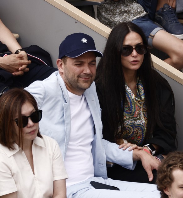 epa09997483 US actor Demi Moore (C) and Swiss chef Daniel Humm (C-R) watch as Rafael Nadal of Spain plays Casper Ruud of Norway in their Men?s Singles final match during the French Open tennis tournam ...