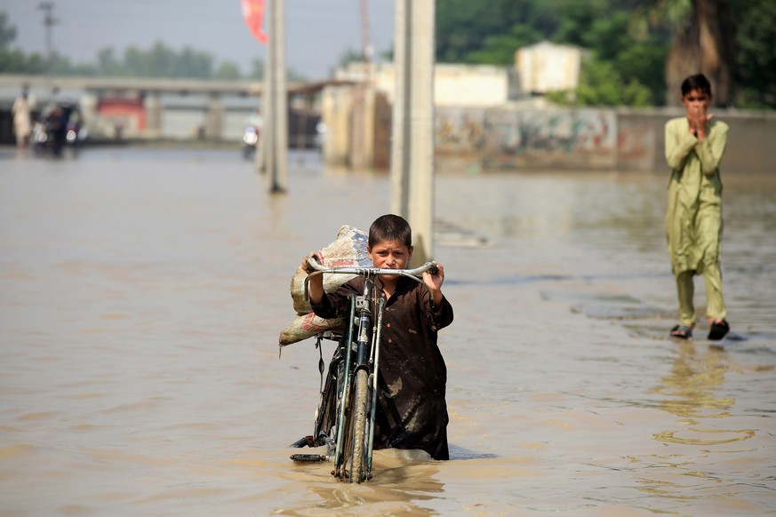 epa10147030 A boy wades through a flooded area following heavy rains in Nowshera District, Khyber Pakhtunkhwa province, Pakistan, 30 August 2022. According to the National Disaster Management Authorit ...