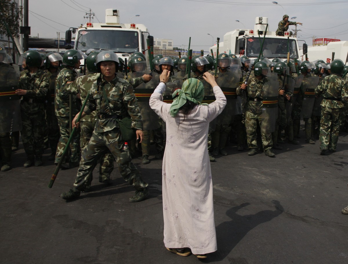 In this photo taken Tuesday, July 7, 2009, a Uighur woman protests before a group of paramilitary police when journalists visited the area in the aftermath of riots in Urumqi in western China's X ...