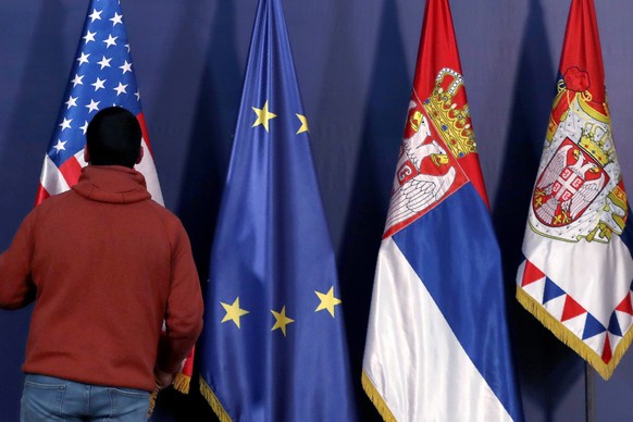 In this photo taken Friday, Jan. 24, 2020, a protocol staff member arranges US, EU and Serbian flags before the press conference of U.S. President Donald Trump&#039;s envoy for the Kosovo-Serbia dialo ...