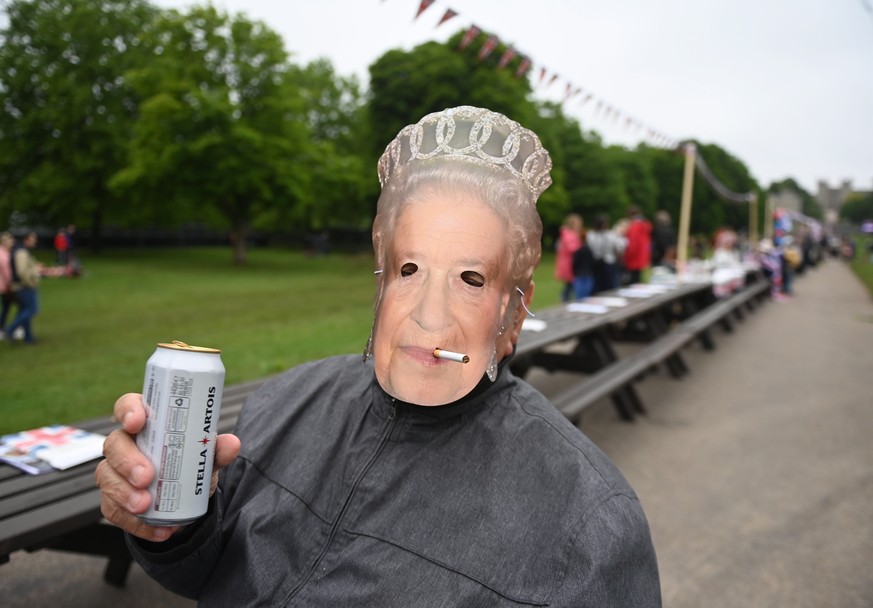 epa09997105 A man wearing a Queen mask enjoys a picnic during The Big Lunch on the Long Walk during the celebrations of the Platinum Jubilee of Britain&#039;s Queen Elizabeth II, in Windsor, Britain,  ...