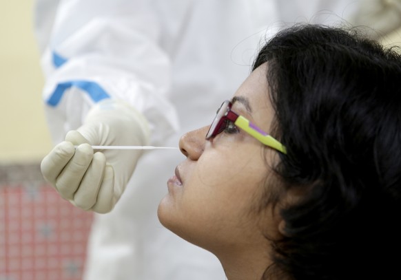 epa08692731 A government health worker takes swab samples for a COVID-19 Rapid Antigen detection test within Roxy Cinema Hall amid the coronavirus pandemic, in Kolkata, India, 24 September 2020. In ce ...