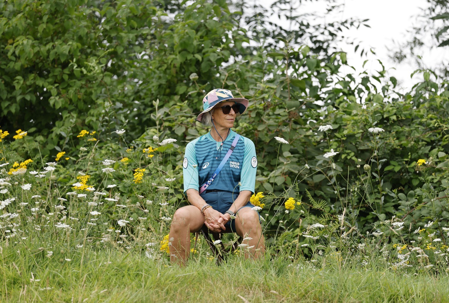 epa11521535 A volunteer sits among the flowers near the 4th green during the third round of the Paris 2024 Olympic Games Men&#039;s Individual Stroke Play golf competition at Le Golf National in Guyan ...
