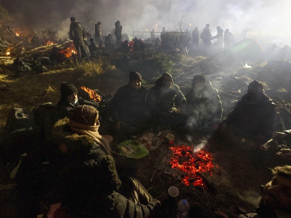 Migrants warm themselves near a fire at the checkpoint &quot;Kuznitsa&quot; at the Belarus-Poland border near Grodno, Belarus, on Tuesday, Nov. 16, 2021. Some of the migrants have children with them a ...