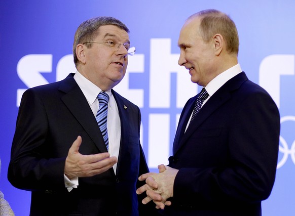 FILE - Russian President Vladimir Putin, right, greets International Olympic Committee President Thomas Bach at an event welcoming IOC members ahead of the upcoming Winter Olympics at the Rus Hotel, F ...